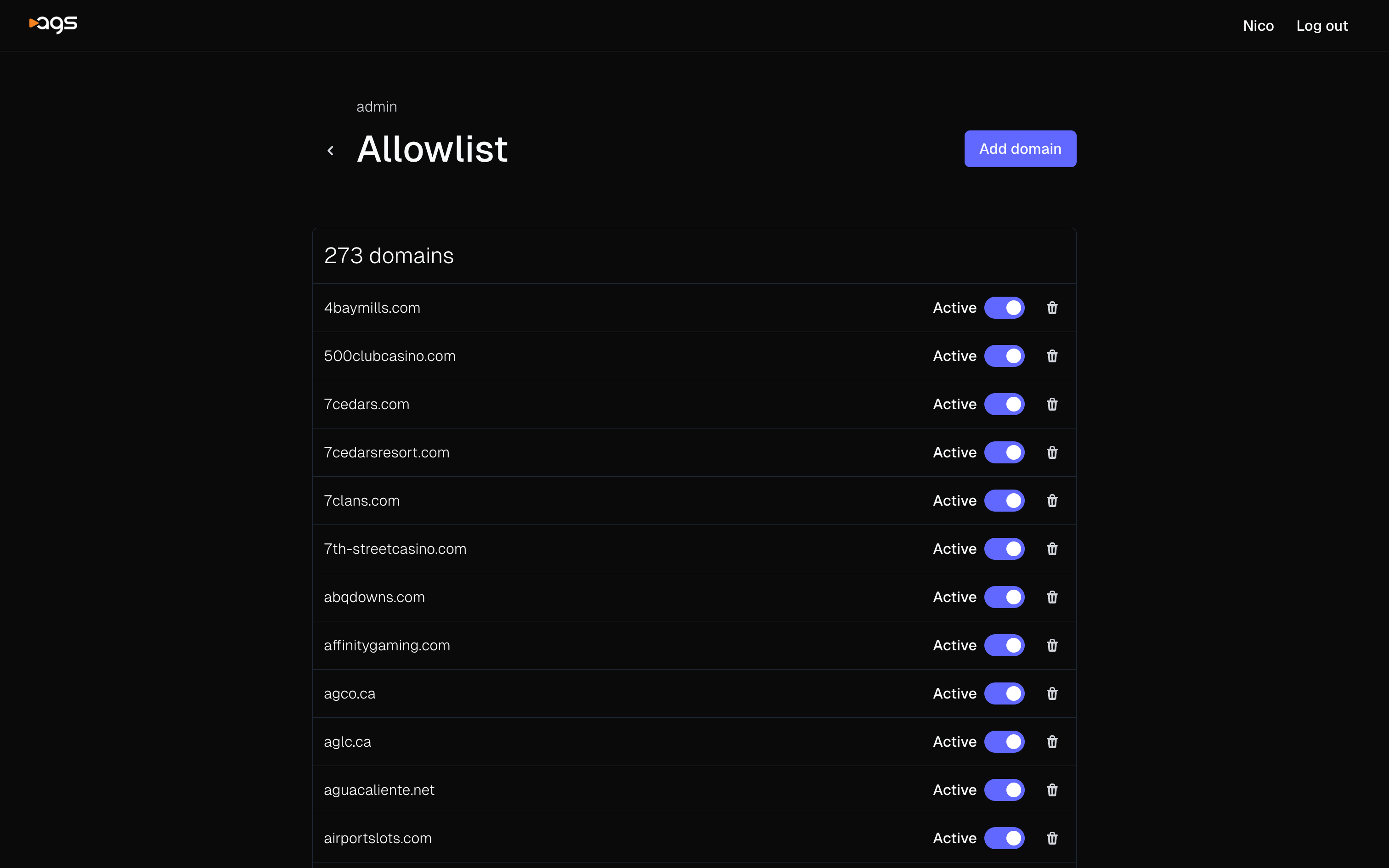 A webpage displaying an allowlist management interface with a black background. The AGS logo appears in the top-left corner, with the user's name and "Log out" options in the top-right. The page shows "admin" above the main "Allowlist" heading. There's a purple "Add domain" button in the top-right of the content area. The interface shows "273 domains" and lists several domain names including casino and gaming websites (4baymills.com, 500clubcasino.com, 7cedars.com, 7cedarsresort.com, 7clans.com, 7th-streetcasino.com, abqdowns.com, affinitygaming.com, agco.ca, aglc.ca, aguacaliente.net, airportslots.com). Each domain has an "Active" toggle switch (all enabled) and a trash icon for deletion.