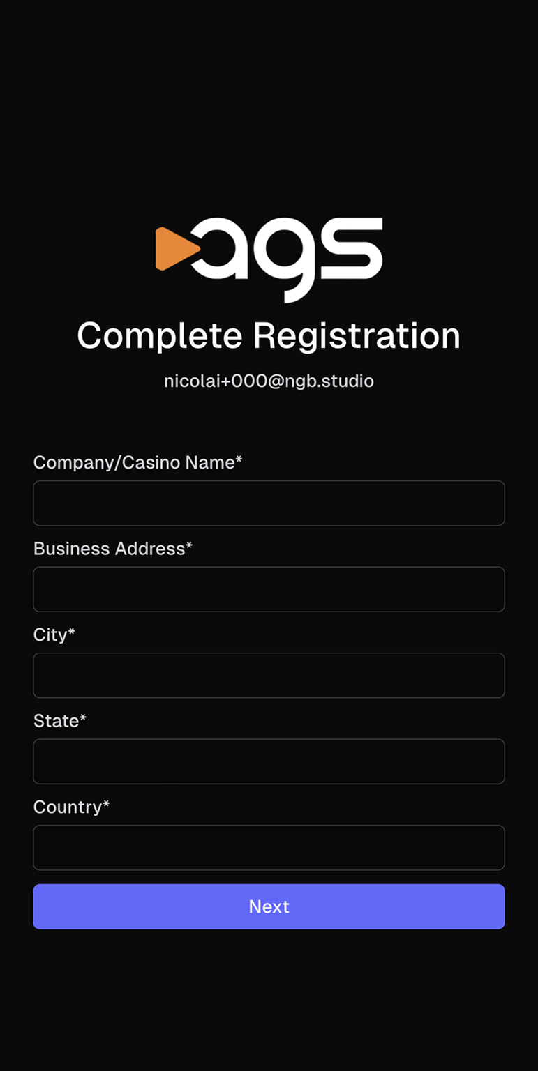 A registration screen with the ags logo (featuring an orange play button triangle next to white letters) on a black background. The page displays "Complete Registration" as a heading, with an email address "nicolai+000@ngb.studio" shown below it. The form contains five required fields marked with asterisks: Company/Casino Name, Business Address, City, State, and Country. All fields are empty text inputs. A purple button labeled "Next" appears at the bottom of the screen.