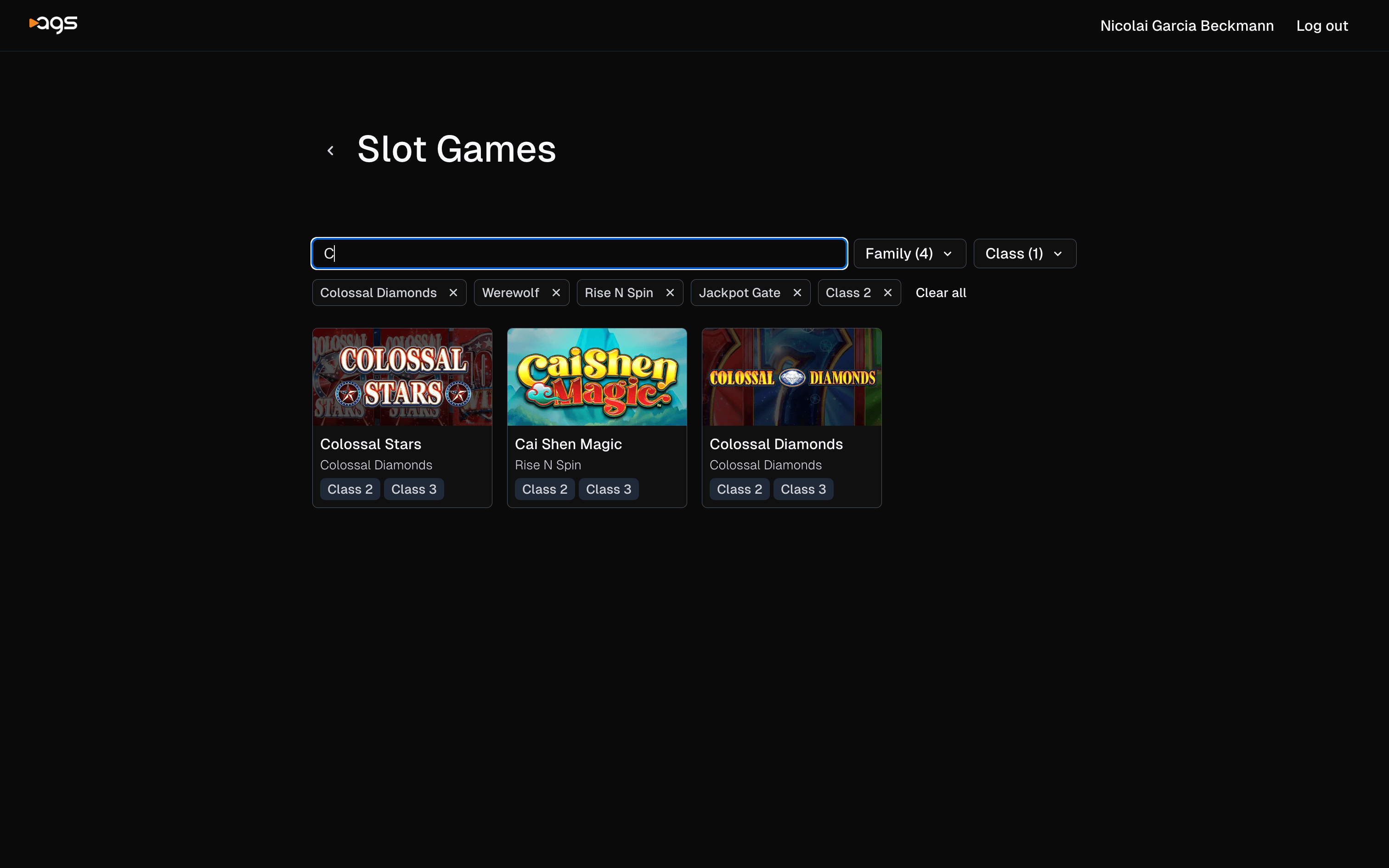 A webpage showing filtered slot game results with a black background. The AGS logo appears in the top-left corner, with "username" and "Log out" options in the top-right. The page is titled "Slot Games" and displays a search field with active filters shown as tags below: "Colossal Diamonds," "Werewolf," "Rise N Spin," "Jackpot Gate," and "Class 2," along with a "Clear all" option. The Family dropdown shows "(4)" and Class dropdown shows "(1)". Three slot games are displayed in a grid: "Colossal Stars," "Cai Shen Magic," and "Colossal Diamonds." Each game card includes the title, subtitle, and class designations (Class 2 and Class 3).